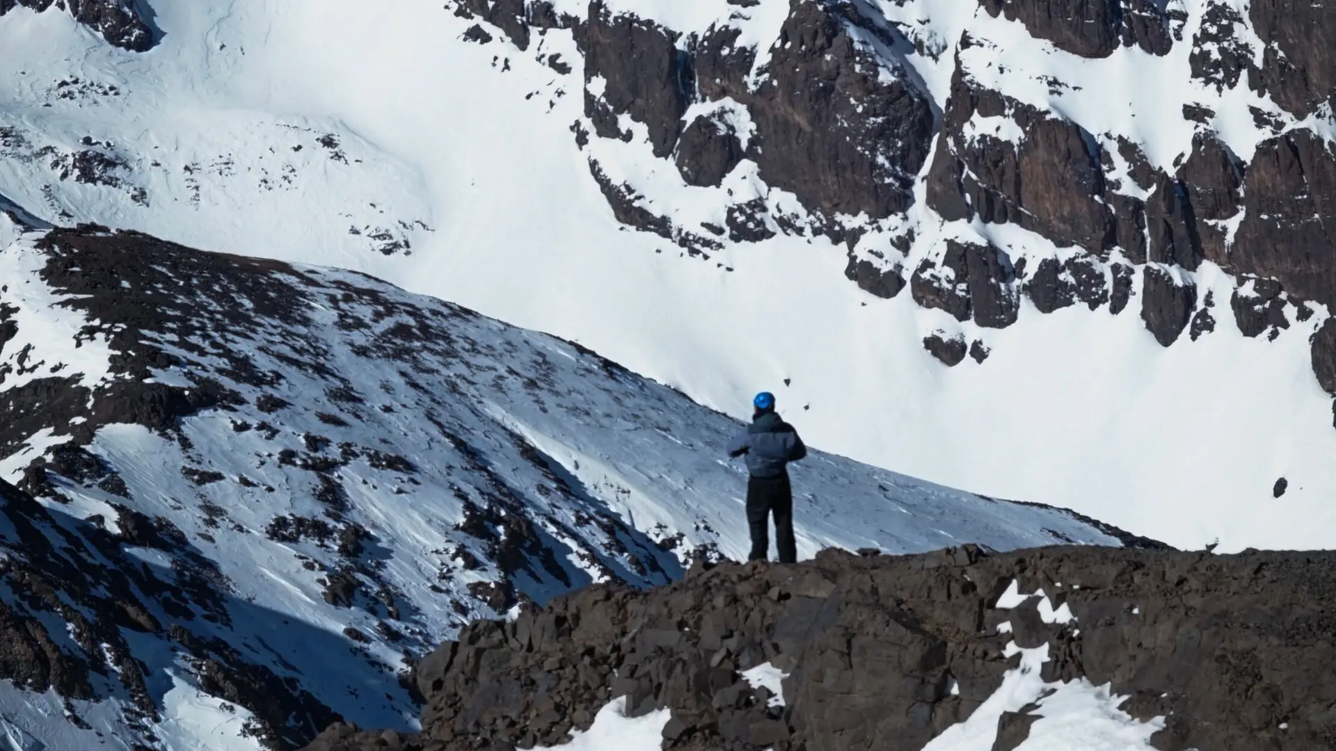 A trekker in winter gear on a snowy High Atlas summit