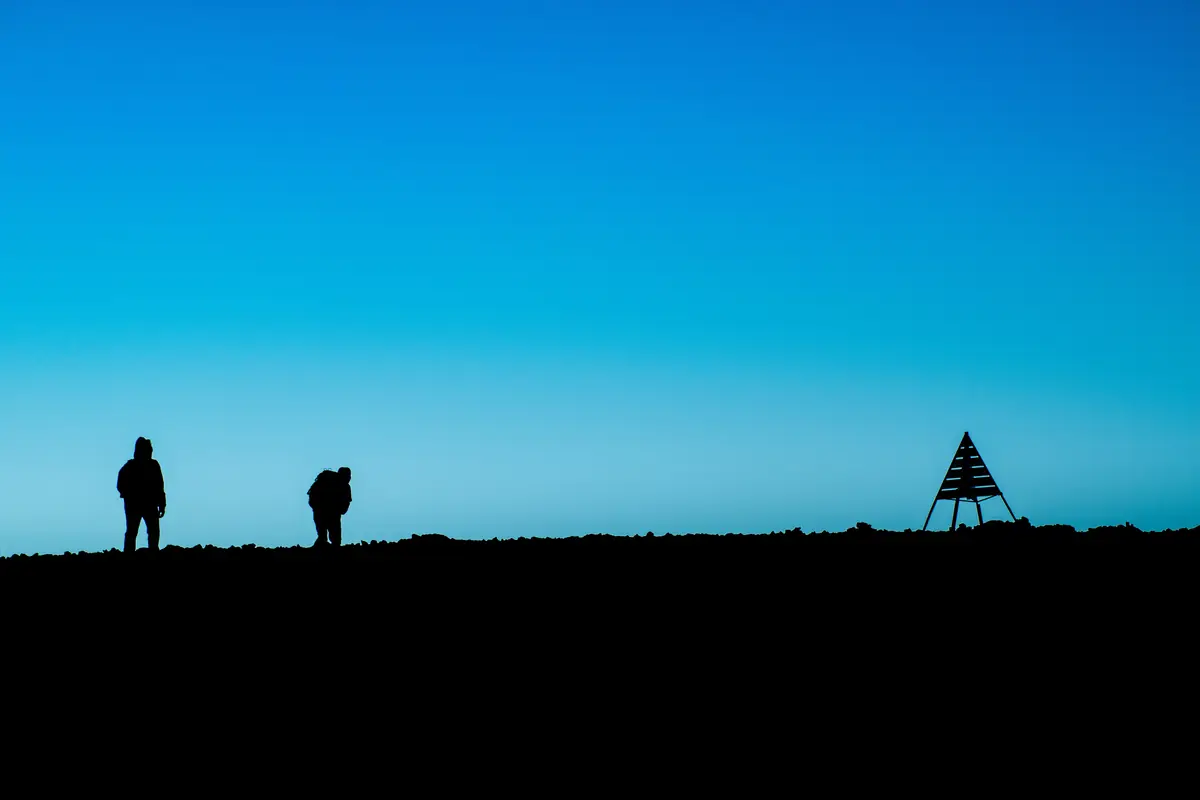 Two trekkers on the summit of Jbel Toubkal beside the summit pyramid at dawn